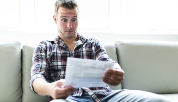 Shocked man holding some documents on sofa livingroom