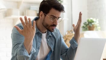 Angry frustrated young man furious about laptop computer malfunction