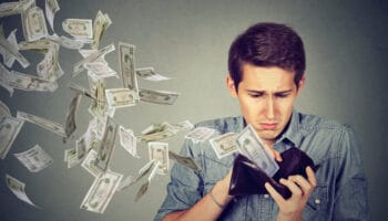 Sad man looking at wallet with money dollars flying away