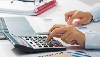 businesswoman working on desk using calculator analyzing finance